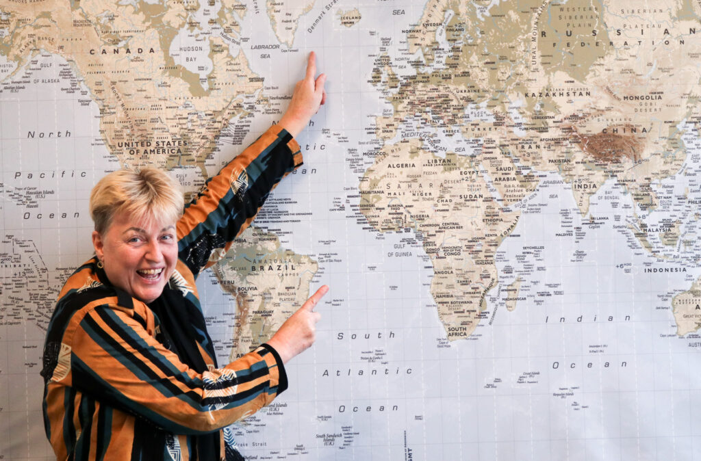A photo of Ebba from Iceland, pointing at a world map 