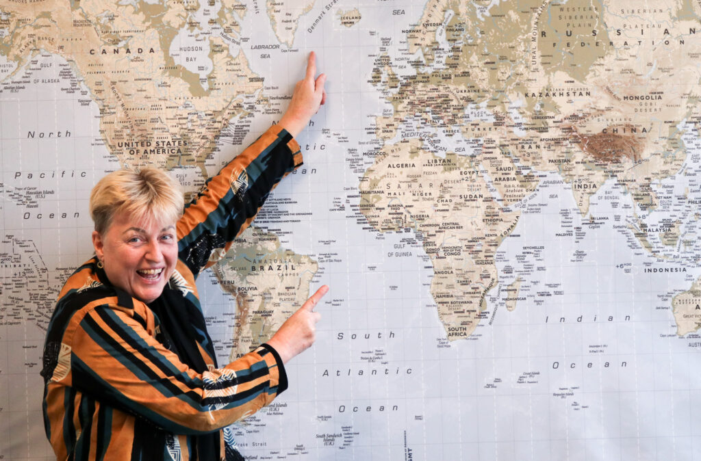 A photo of Ebba from Iceland, pointing at a world map