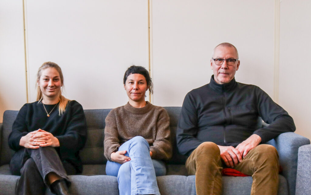 Photo of three persons sitting in  a sofa