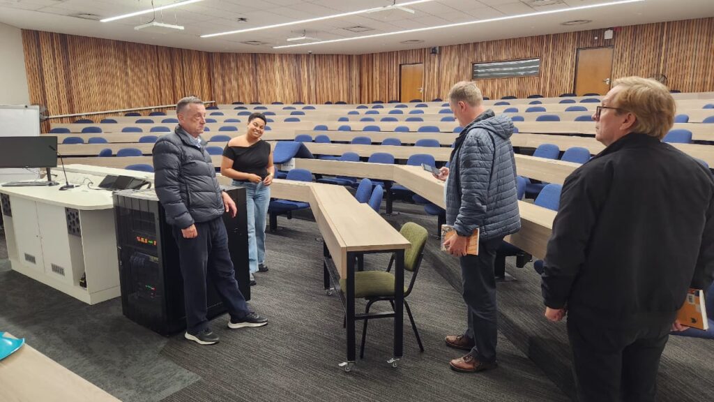 Bilde av tre menn og en dame i et auditorium