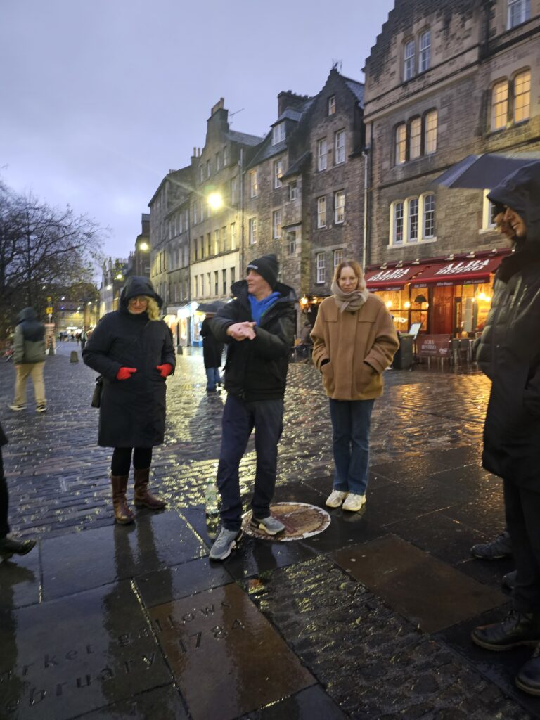 Bilde fra Grassmarket i Edinburgh. En mann står og gestikulerer med armene. Rundt han står flere andre og ser på. 