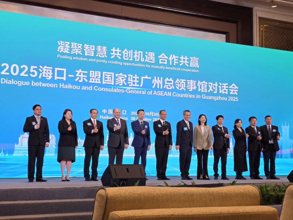 Bilde av en rekke mennesker med asiatisk utseende. Bak dem er en blå vegg med kinesisk tegn.