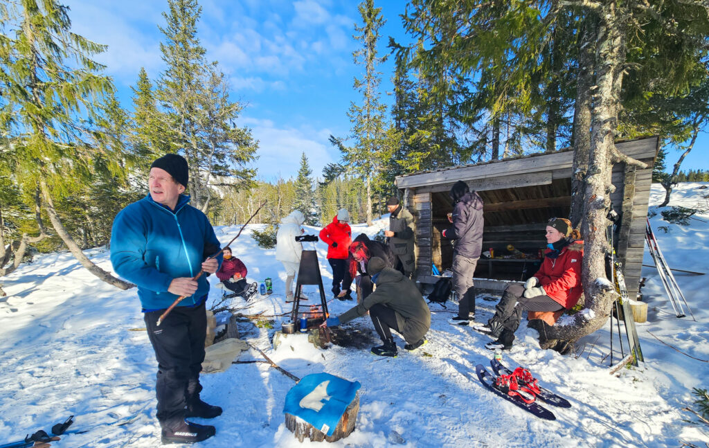 Bilde av personer i vinterklær ved en gapahuk. 
