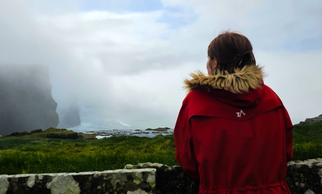 Bilde av en kvinne som kikker mot en klippe ved havet 