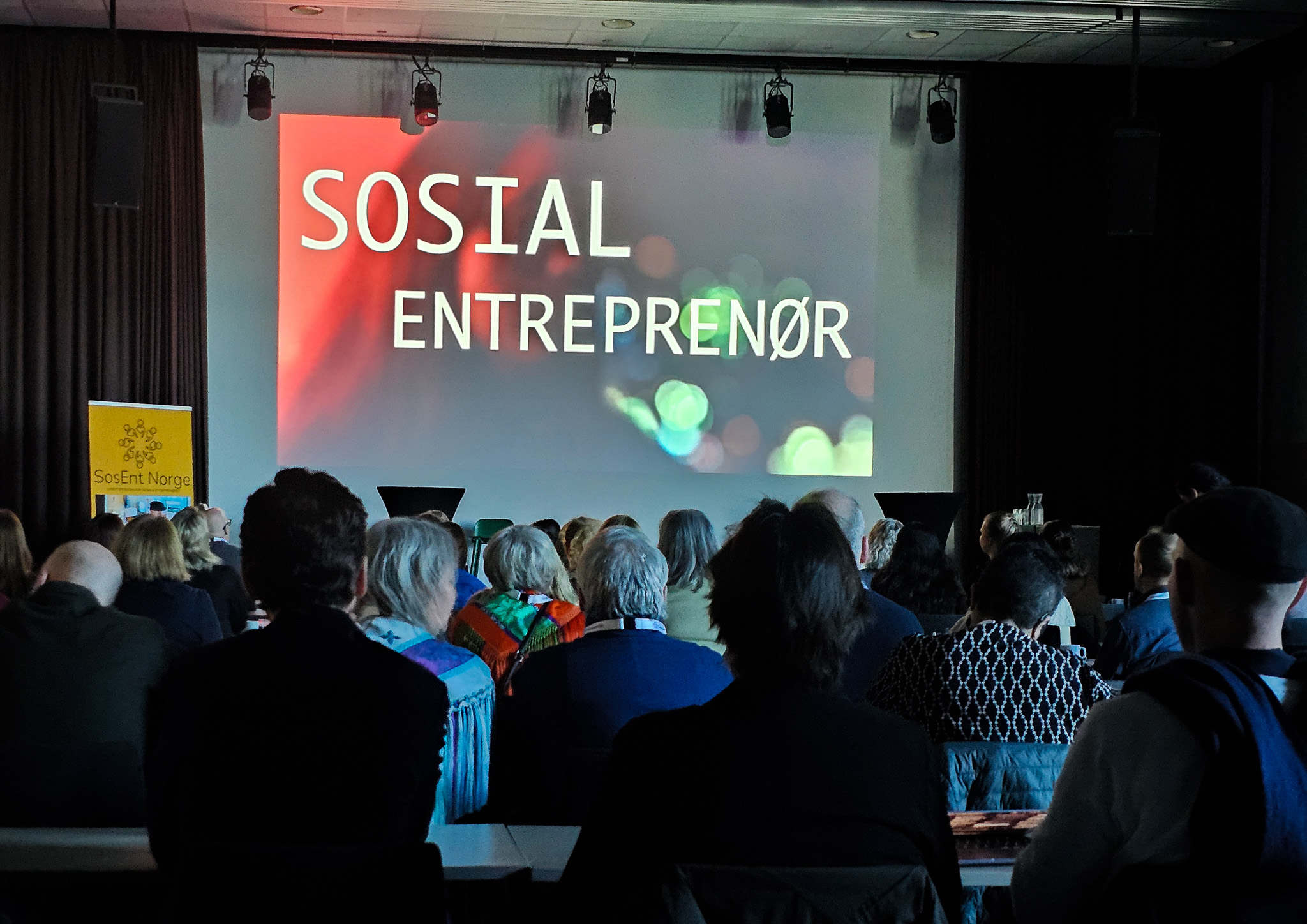 Fullt konferanselokale. På lerretet står det: sosial entreprenør